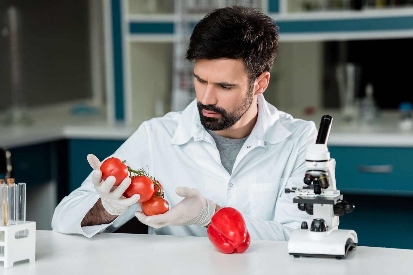 Bearded scientist in white coat working examining vegetables in laboratory